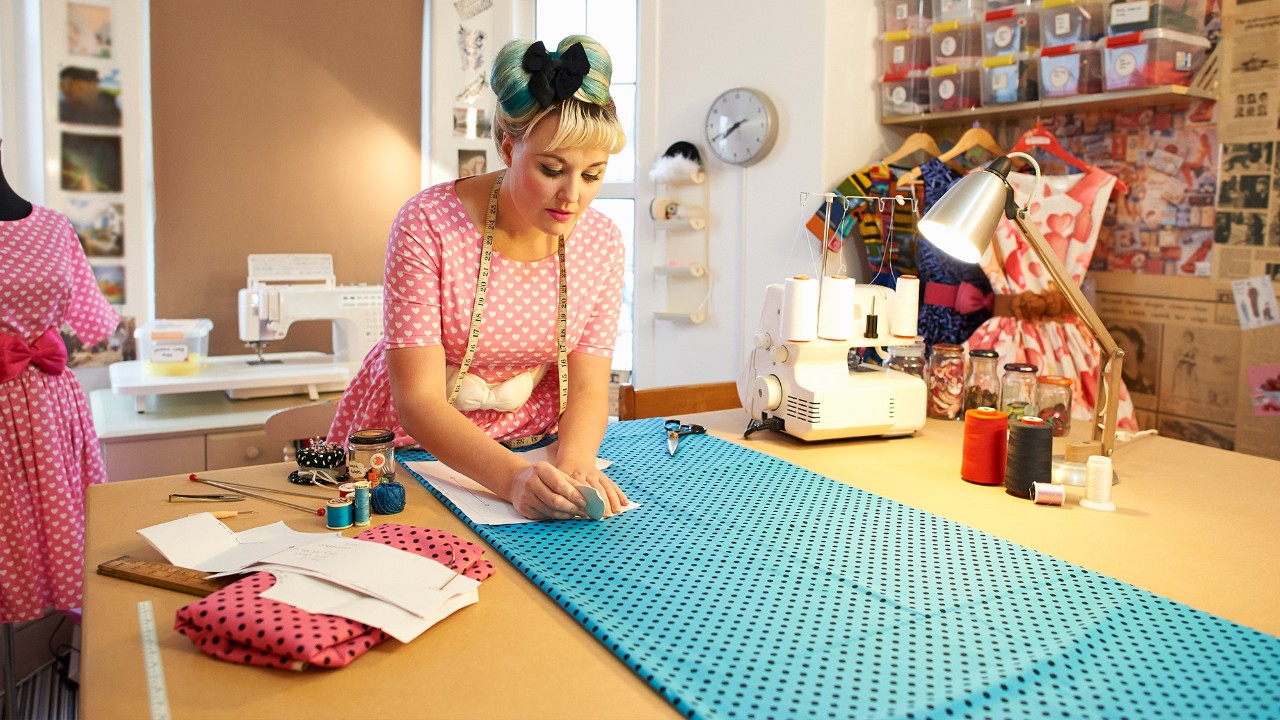 A woman is sewing clothes; image used for "getting financially fit" article.