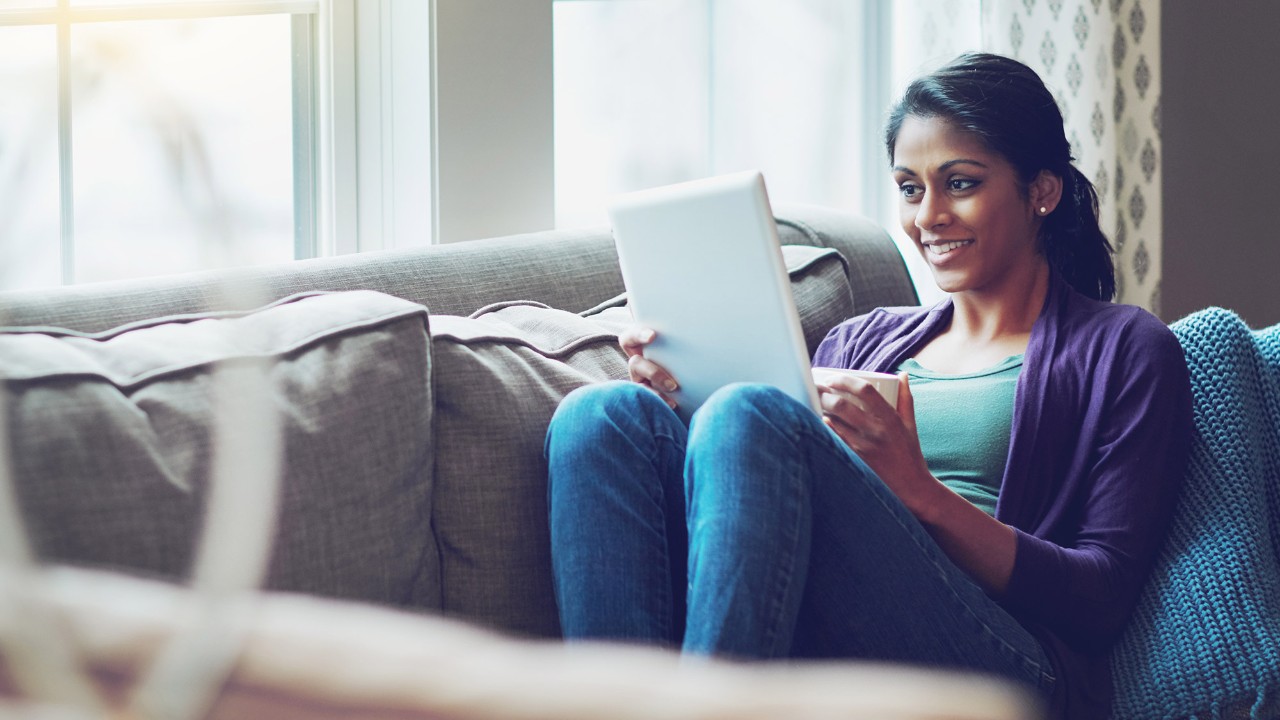 Happy woman using tablet on a couch; image used for HSBC Sri Lanka Ways to Bank