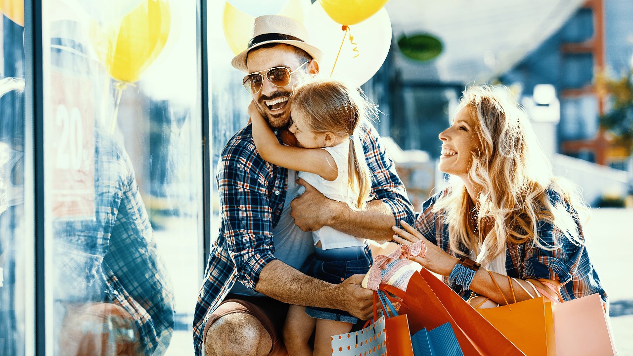 Parents holding their girl happily and with shopping bags and ballons outside a shop window; image used for HSBC LK credit cards rewards page